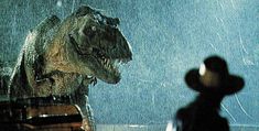 a person standing in the rain next to a dinosaur