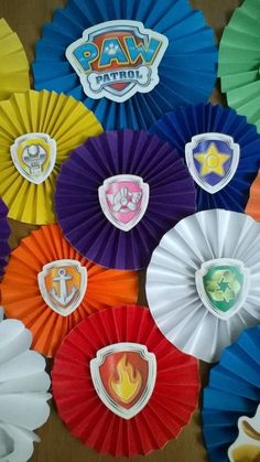 there are many different colored paper fans on the table with each one's own logo