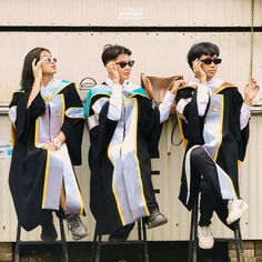 three graduates sitting on chairs with their cell phones up to their ears and one holding a basket