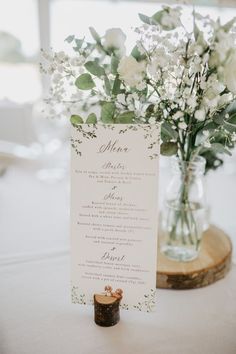 a menu card sitting on top of a table next to a vase filled with flowers