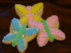 three decorated cookies sitting on top of a brown cloth covered table next to each other