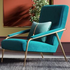 a blue chair sitting in front of a painting on the wall next to a potted plant