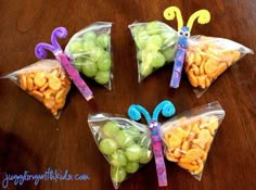 four bags filled with grapes and nuts on top of a wooden table in the shape of butterflies