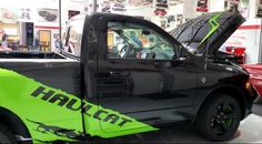 a pick up truck with the hood open in a showroom filled with other vehicles