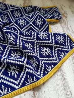 two blue and yellow knitted scarves sitting on top of a white wooden floor