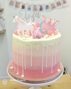 a pink and white cake with unicorn decorations on top