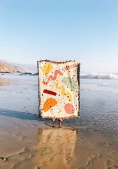 a person standing in the water holding up a blanket with an image of fish on it