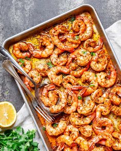 a pan filled with cooked shrimp and garnished with parsley on the side