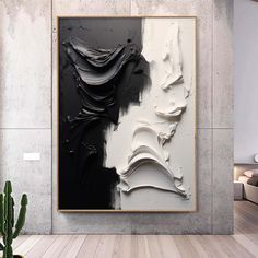 an abstract painting hangs on the wall next to a cactus in a modern living room