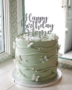 a green birthday cake sitting on top of a table next to a window with the words happy birthday behind it