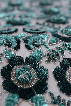 green and silver beaded fabric with flowers on it