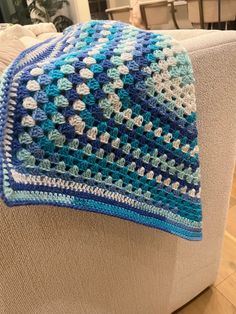 a blue and white crocheted blanket sitting on top of a couch