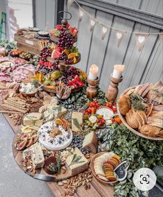 an assortment of cheeses, meats and vegetables on a table with bunting