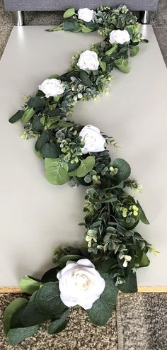 white flowers and greenery are arranged in the shape of a letter e on a table