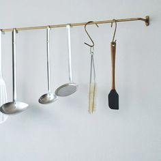 there are spoons, spatulas and other kitchen utensils hanging on the wall