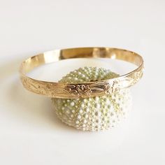 Traditional Hawaiian heirloom bangle is make with decorative floral pattern wire. Bangle is hand- formed, hammered and polished for a stunning texture and shine. It looks great worn alone or paired with other shell and charm bangles to create a chic, fun beachy look. Bangle is about 8mm wide 1.2 mm thick. Each bangle is custom made to order so can not be return or exchange for that reason. Please don't hesitate to contact me if you have any questions at all before ordering. PLEASE NOTE THERE IS Heirloom Gold Bangle Bracelet With Intricate Design, 14k Gold Bracelets With Intricate Design For Wedding, 14k Gold Wedding Bracelets With Intricate Design, 14k Gold Bangle With Intricate Design For Anniversary, Anniversary 14k Gold Bangle With Intricate Design, 14k Gold Bangle With Intricate Design As Gift, Heirloom Gold Bangle With Filigree, Adjustable 14k Gold Bangle For Wedding, Gold 14k Wedding Bangle