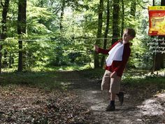 a young boy is playing with a kite in the woods on a path through trees