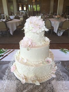 a three tiered wedding cake sitting on top of a table covered in white cloths