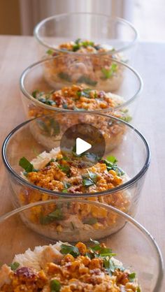 three glass bowls filled with food sitting on top of a wooden table