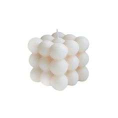 a bunch of white balloons floating on top of a white surface with a candle in the middle