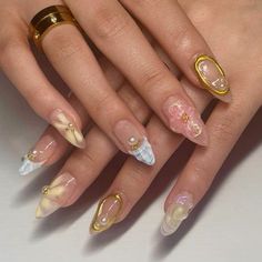 a woman's hand with gold and white manies on her nails, holding a ring