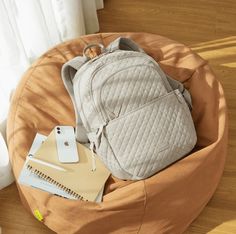 a backpack sitting on top of a bean bag chair next to a cell phone and notebook