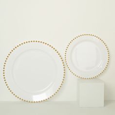 two white plates with gold beading on them