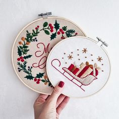 two hand embroidered christmas stockings and sleighs on white wall hangings with red thread