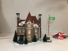 a toy model of a castle with trees and flags on the table next to it