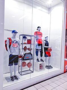 two mannequins dressed in red and white shirts with basketball gear behind them