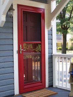 a red door on the side of a blue house with a glass case in it