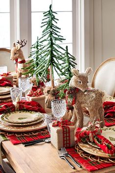 the table is set for christmas dinner with red and green plaid napkins, deer figurines