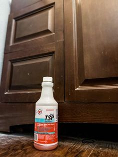 a bottle of tsp sitting on the floor in front of a brown cabinet door