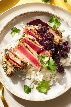 a white plate topped with rice and meat covered in cranberry sauce, garnished with cilantro