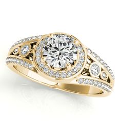 a yellow gold engagement ring with diamonds on the sides and an intricate band around it