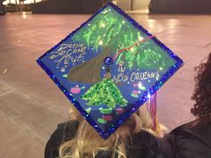 a woman wearing a blue graduation cap with trees on it