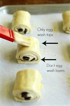 rolled up food items on a baking sheet with an egg wash top and red spatula