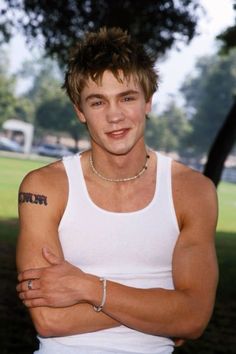 a man with his arms crossed wearing a white tank top