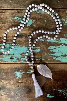 This 108-bead mala, or prayer bead necklace is made with white turquoise, white lava and wood beads with a white tassel and silver filigree leaf.  Each bead is hand-knotted on grey hemp cord.  White turquoise is said to aid in intuition and meditation, while white lava is said to strengthen one's connection to mother earth. White Spiritual Jewelry With Wooden Beads, Spiritual White Jewelry With Wooden Beads, White Bohemian Jewelry With Wooden Beads, Bohemian White Jewelry With Wooden Beads, Elegant White Beaded Necklace For Meditation, White Gemstone Beads Mala For Healing, White Wooden Beads Jewelry For Meditation, White Wooden Beaded Jewelry For Meditation, Adjustable White Mala With 8mm Beads