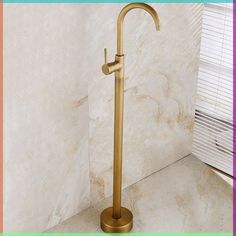 a gold faucet sitting next to a window in a bathroom