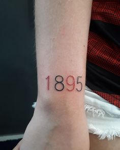 a woman's wrist tattoo with the number nineteen five printed on her left arm