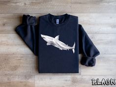 Shark Sweatshirt, Watercolor Shark Shirt, Cool Shark Tshirt, Ocean Sweater, Sea Creature Tee, Shark Lover Tee, Cool Animal Shirt, Shark Tee 🦈 Immerse yourself in the awe-inspiring world of marine art with our Watercolor Shark Shirt, featuring an artistic and captivating watercolor design of a shark. This shirt isn't just an outfit; it's a vibrant celebration of the majestic beauty of sharks. 🎨 Adorned with a watercolor shark design, this shirt adds a touch of artistic flair to your wardrobe. The blend of colors creates a visually stunning piece that appeals to those who appreciate the grace and power of these incredible creatures. 👕 Choose from a variety of styles: T-shirt, Sweatshirt, Hoodie, or Youth Shirt. Whether you're exploring the ocean or embracing a cozy day in, there's a style White Crew Neck Top With Shark Design, Ocean Sweater, Shark Sweatshirt, Cool Sharks, Shark Tee, Shark Design, Shark Lover, Marine Art, Shark Shirt