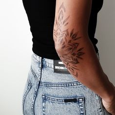 a woman with a tattoo on her arm is standing in front of a white wall