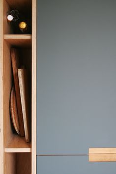 an open cupboard with some wooden items in the bottom drawer and one shelf on the other side