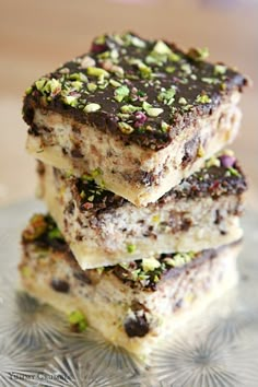 three pieces of cake sitting on top of a glass plate with nuts and chocolate toppings