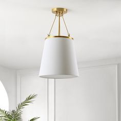 a white lamp hanging from the ceiling in a living room with a potted plant