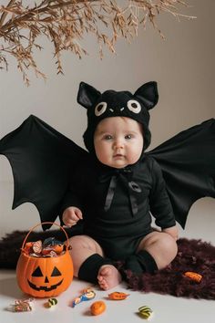 A baby dressed in an adorable bat costume, lying on a flat surface. The baby is wearing a black outfit with bat wings spread out, and a matching black hat with cute eyes and small ears. Bat Baby Costume, Baby Bat Photoshoot, Diy Baby Bat Costume, Easy Diy Baby Halloween Costumes, Diy Halloween Baby Photoshoot, Diy Bat Costume Kids, Fantasia Halloween Bebe, Bat Costume Diy, Cute Bat Costume