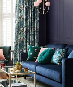 a living room with blue couches and colorful pillows on the sofa, along with a gold coffee table