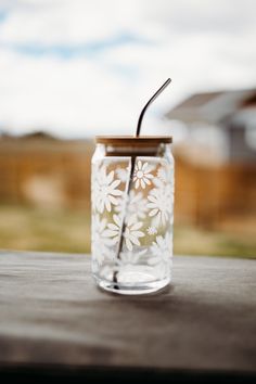 a glass jar with a straw in it sitting on a table outside next to a house