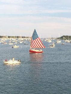 a large body of water with boats and an american flag sailboat in the distance